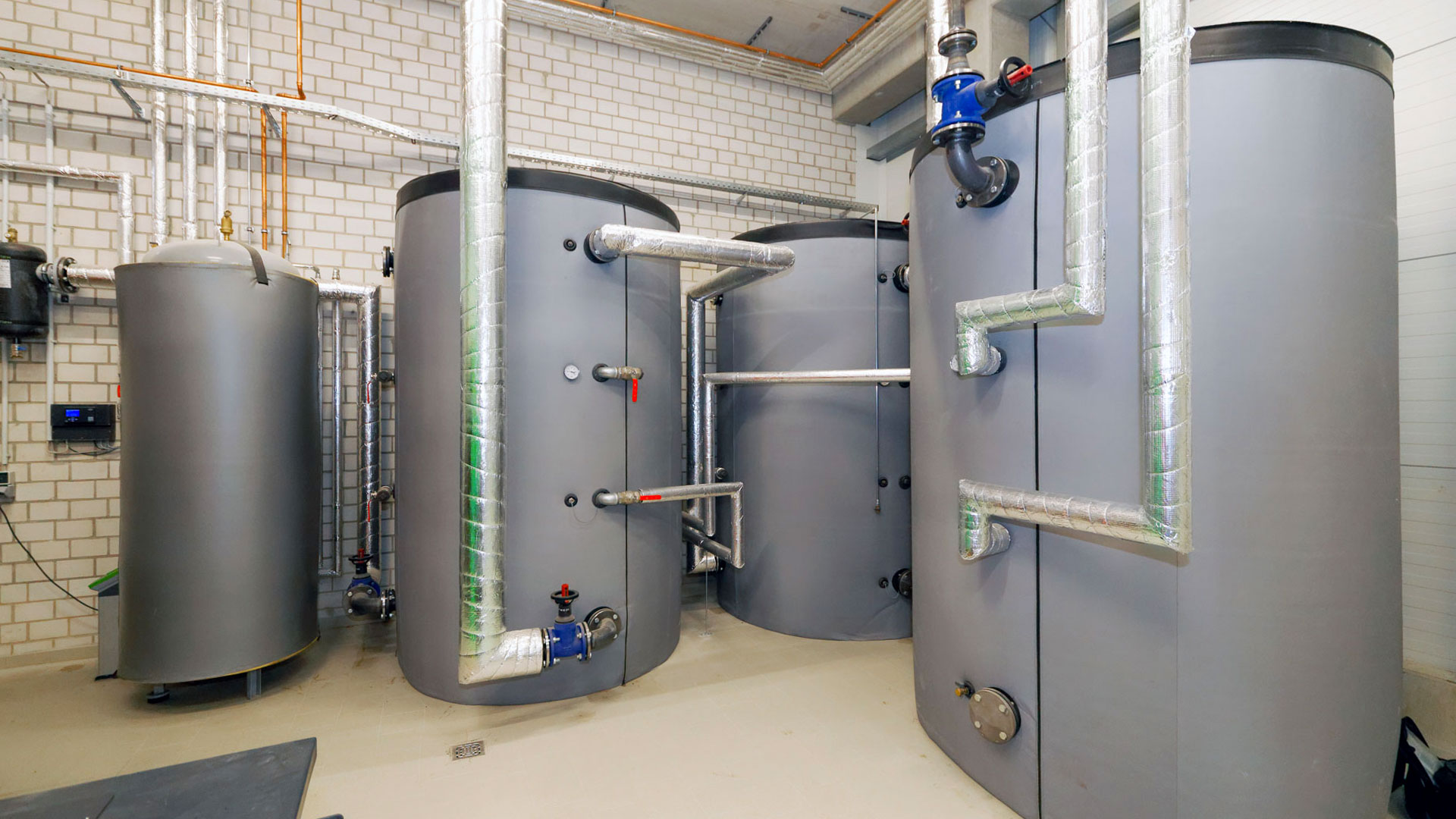 Pufferspeicher mit isolierten Leitungen in einem gemauerten Raum