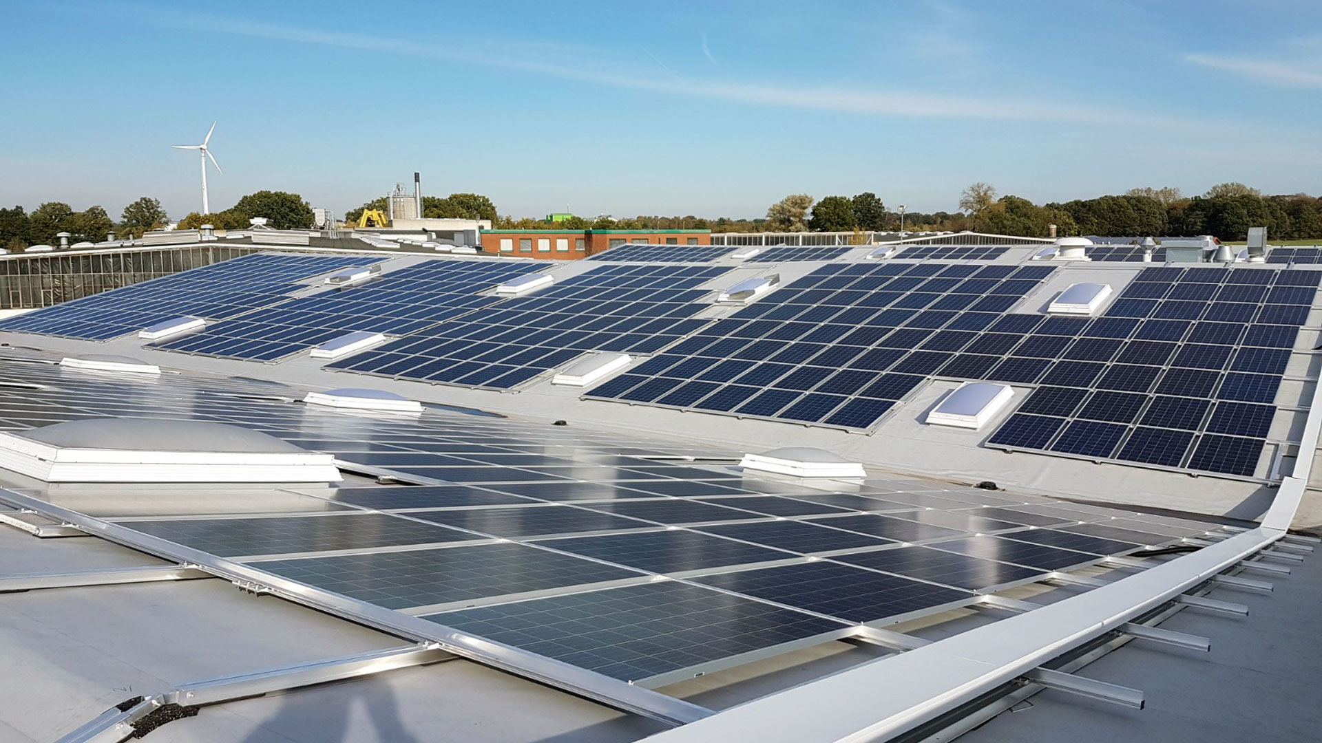 photovoltaikanlage-Hartmann-Beelen-döpik Industriehallendach mit PV-Modulen vor einem blauen Himmel