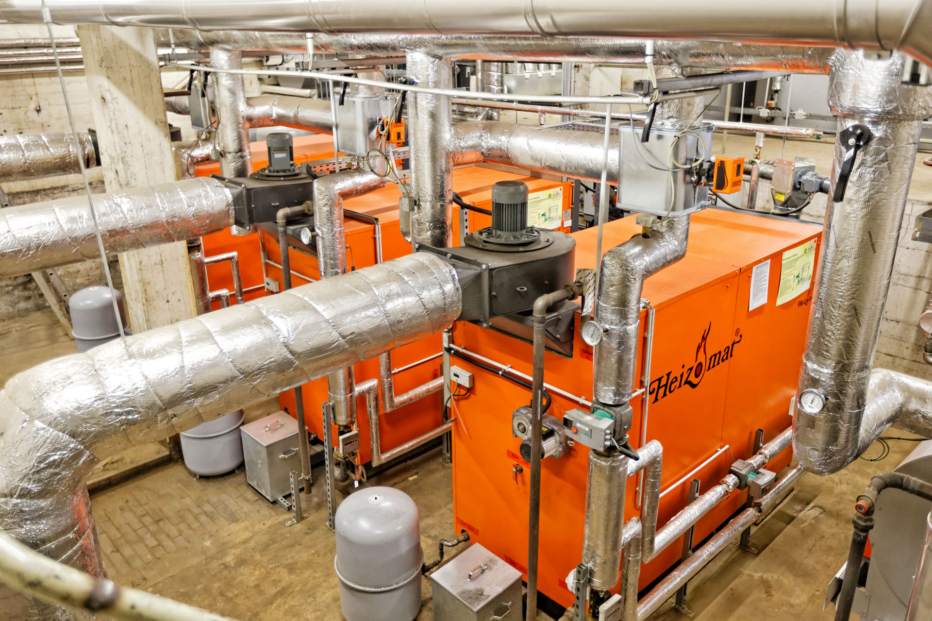biomasseheizung-kaskade-holzpellets Drei Heizomat Pelletheizungen in Heizraum eines Schulgebäudes
