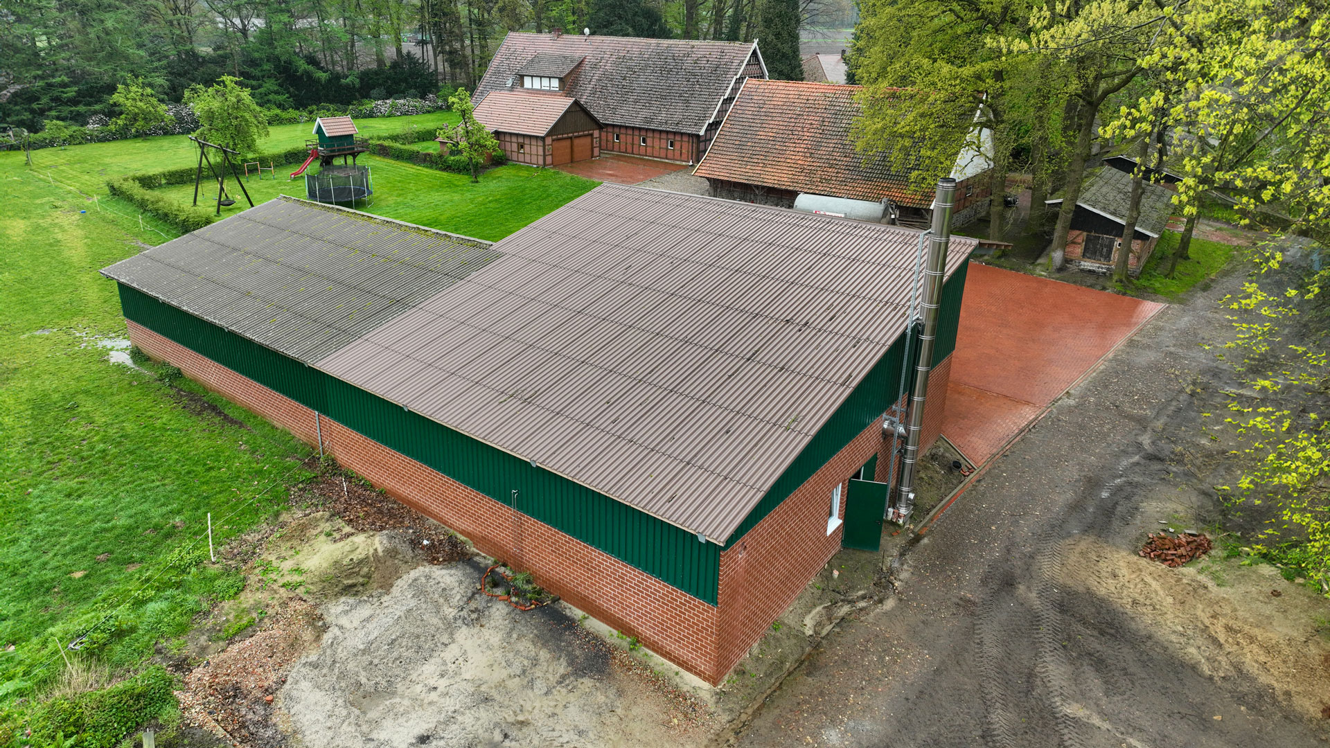 Luftaufnahme eines Schirmschoppens mit Edelstahlkamin auf einem landwirtschaftlichen Betrieb