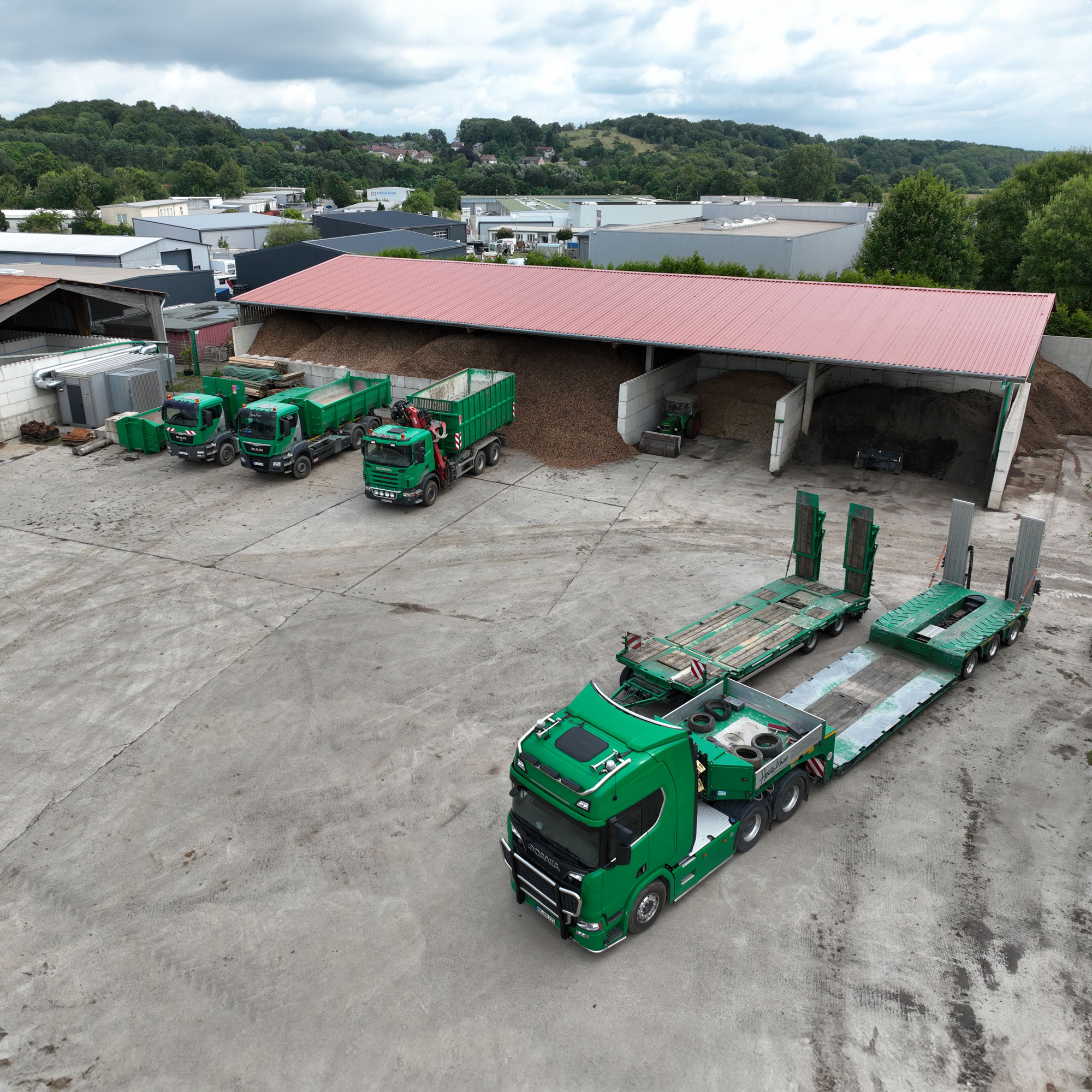 default Luftauifnahme von 4 grünen LKW der Firma Kinze bei der Hackschnitzelproduktion