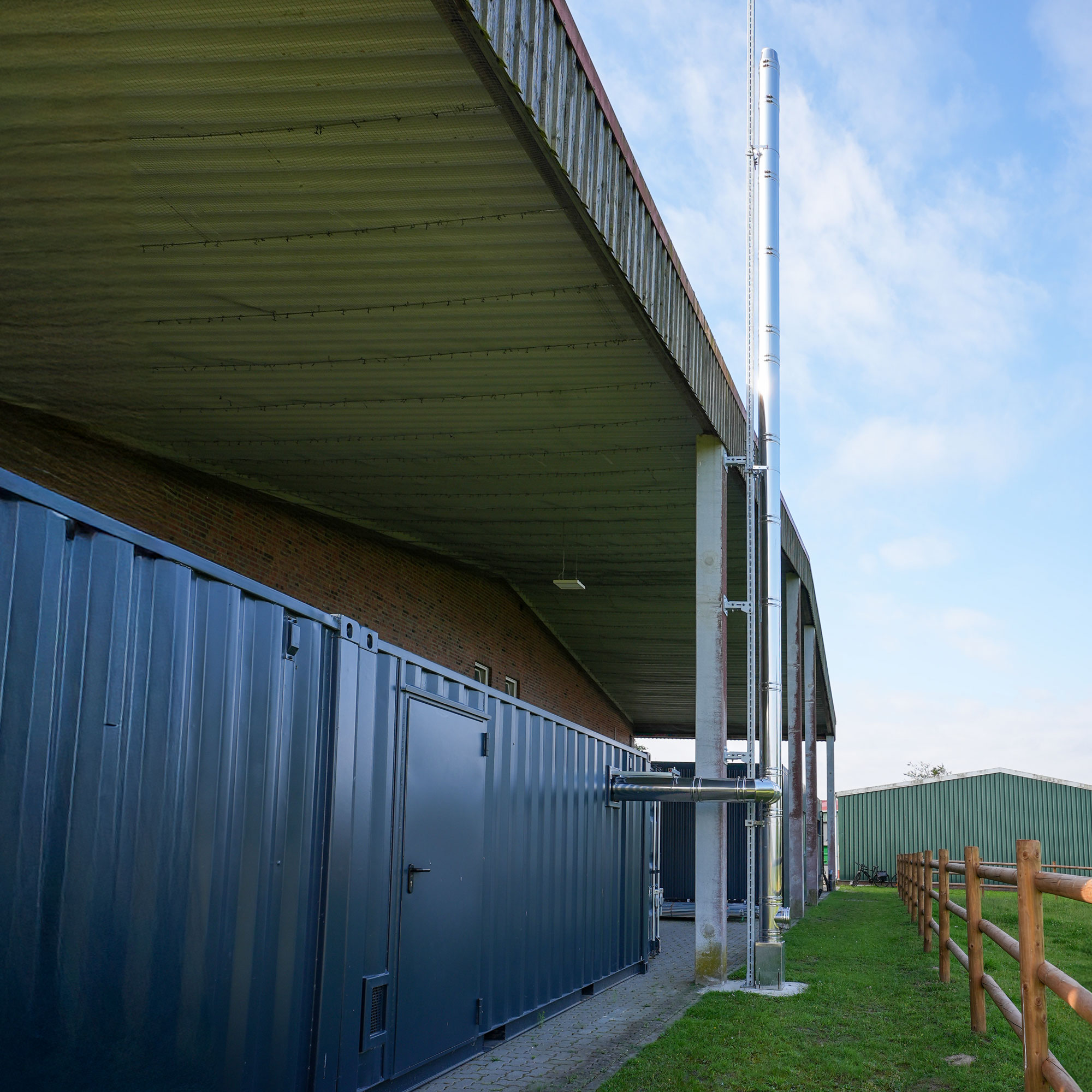 Edelstahlkamin einer Biomasseheizung vor blauem Himmel