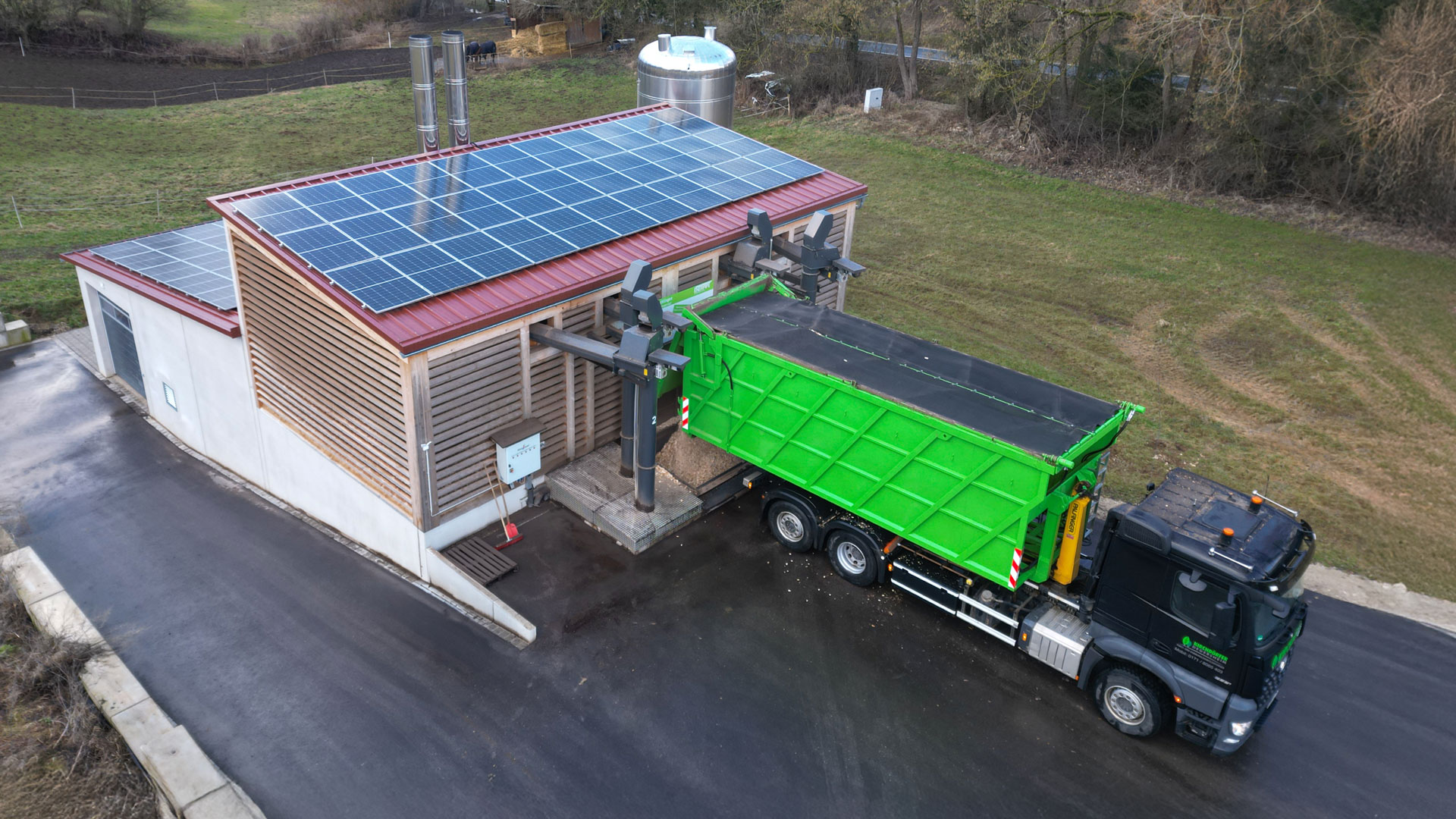 Heizzentrale bei der Befüllung mit Hackschnitzeln mit einem LKW-Kipper und Bunkerbefüllsystemen