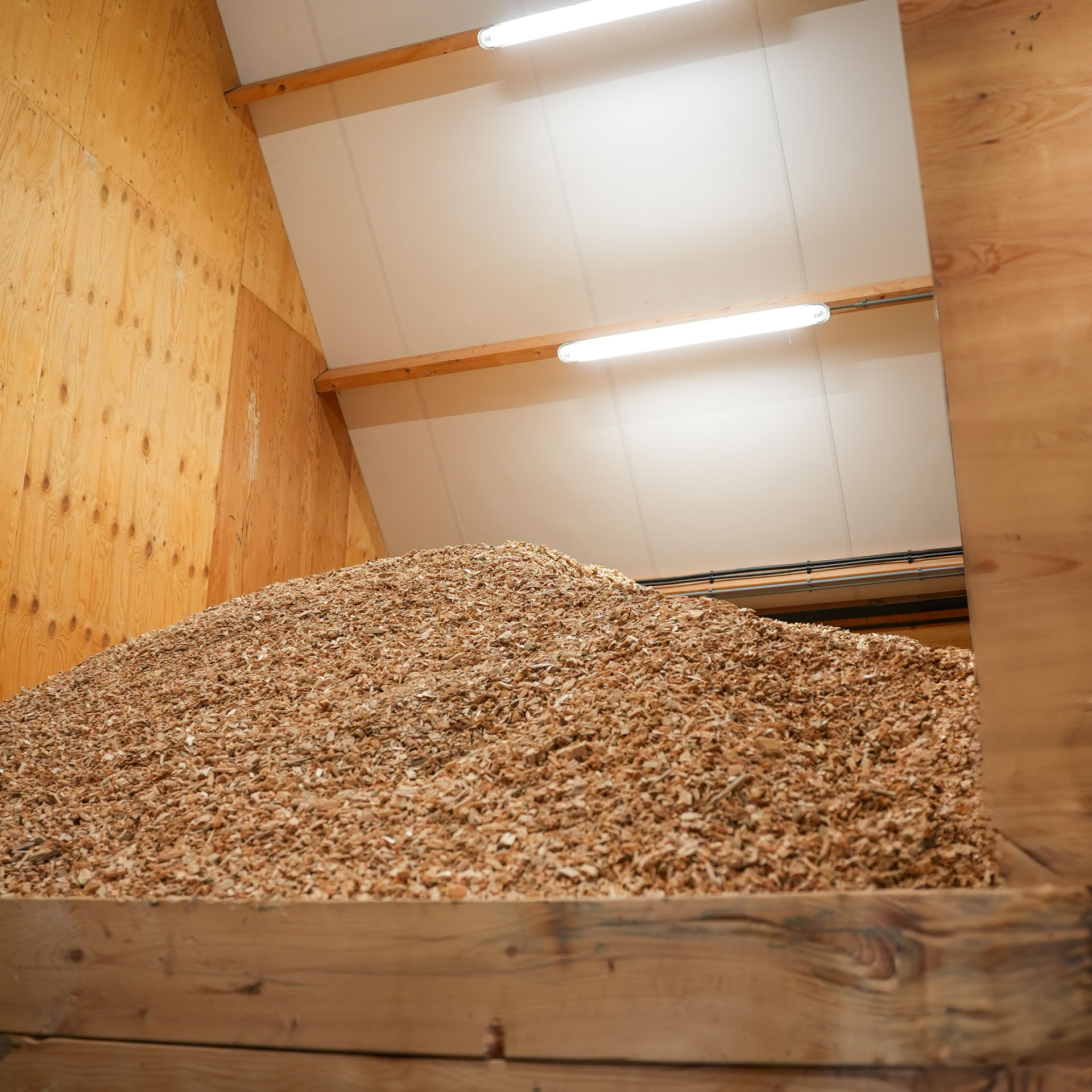 Hackschnitzelbunker in einer Heizzentrale mit Holzwänden und Deckenleuchten