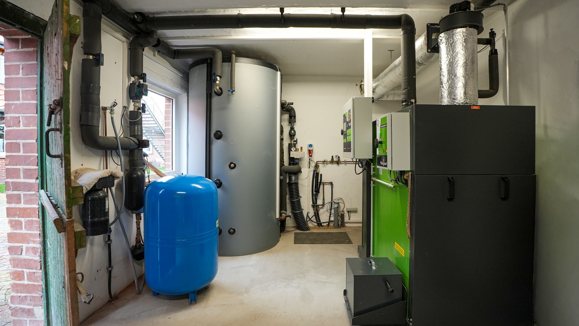Heizungsraum mit einer Heizomat Hackschnitzelheizung, Pufferspeicher, Ausdehnungsgefäß und Leitungsrohren