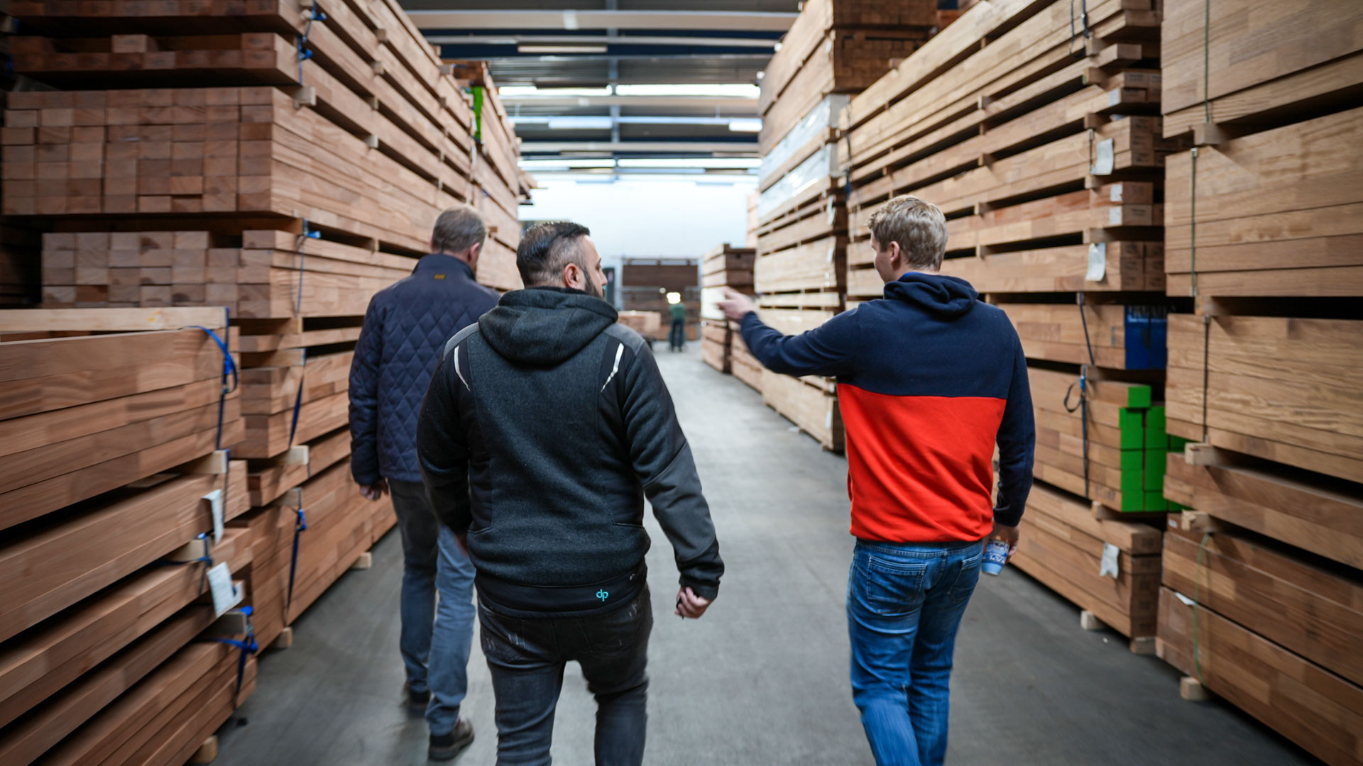 Drei Personen laufen durch einen Holz verarbeitenden Betrieb